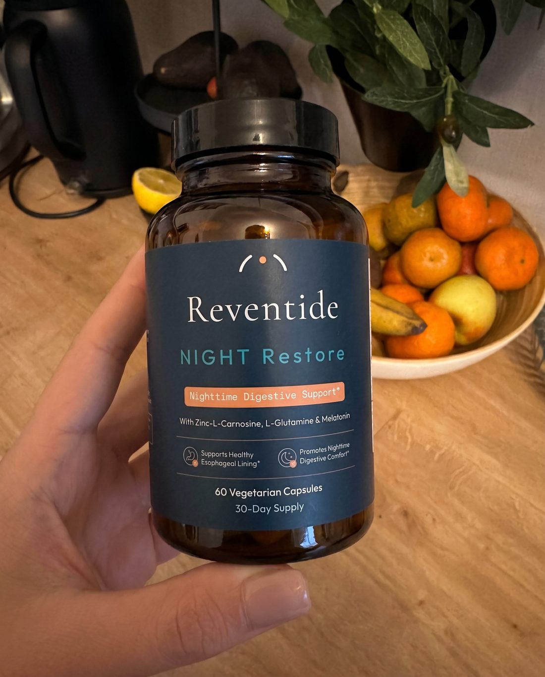 NIGHT Restore bottle held in a hand in a kitchen