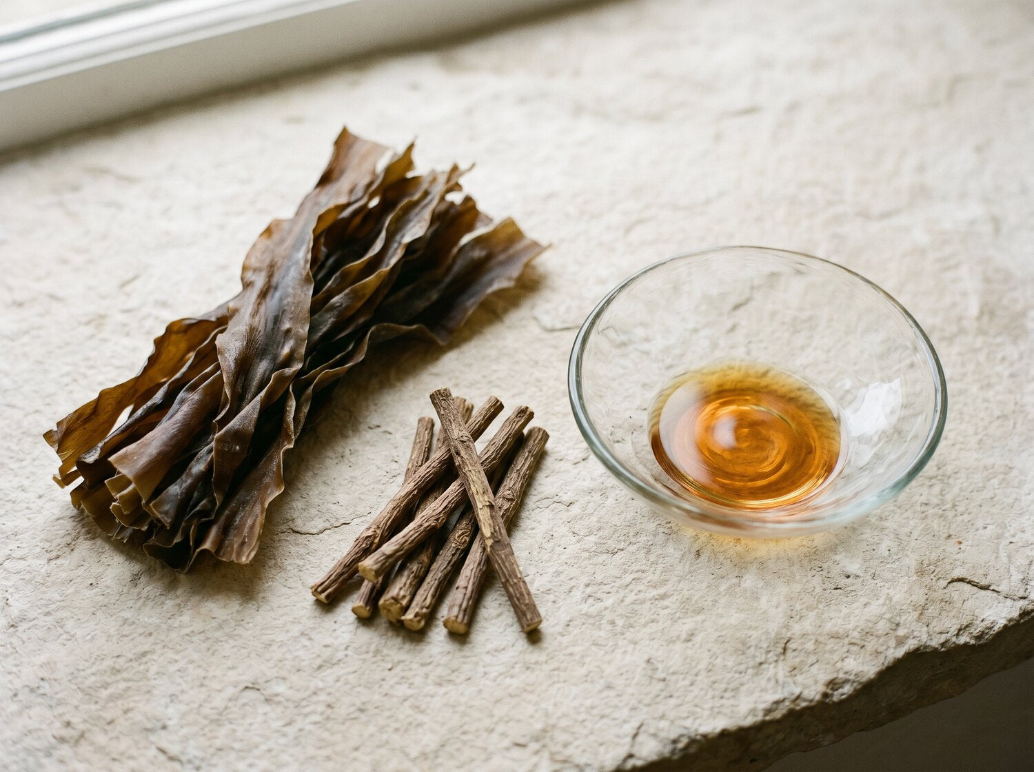 Dried seaweed and licorice root arranged on a stone surface.
